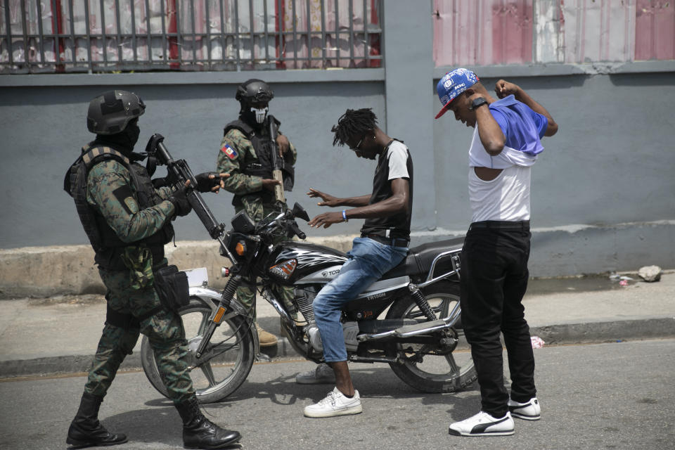 Armed forces check two men who were riding a motorcycle for weapons, at the area of ​​state offices of Port-au-Prince, Haiti, Monday, July 11, 2022. Radio TV Caraibe, a popular radio station in Haiti announced on Monday that it would stop broadcasting for one week to protest widespread violence in the capital. (AP Photo/Odelyn Joseph)