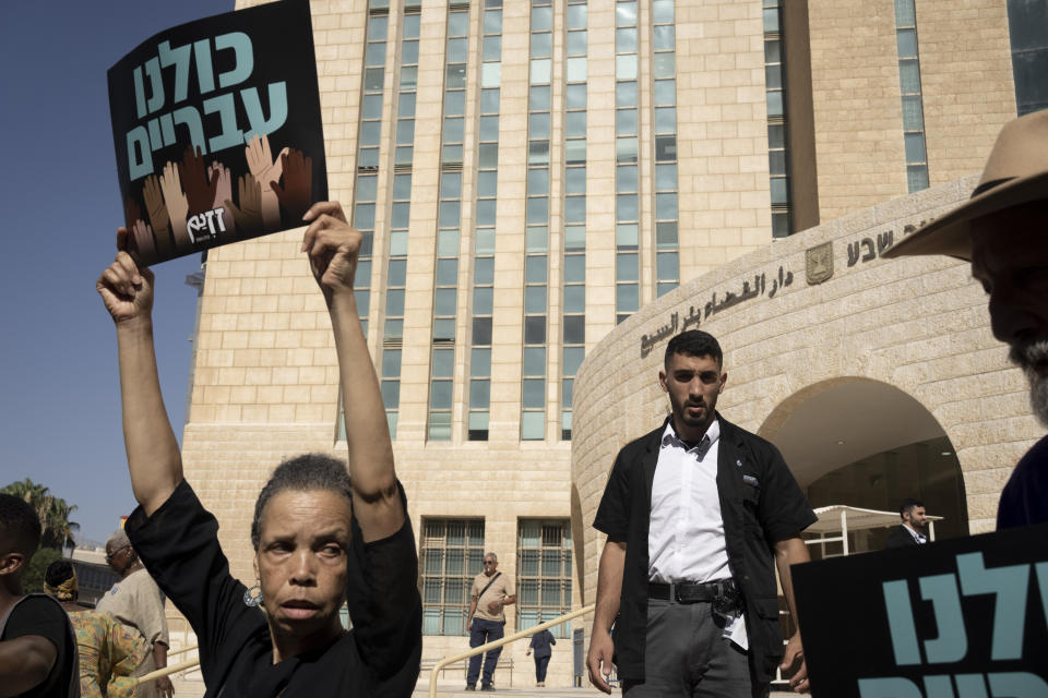 An Israeli court security guard approaches members of the African Hebrew Israelites of Jerusalem to move their rally off of the steps of the District Court in Beersheba, Israel, ahead of a hearing on the deportation orders for dozens from their community, Wednesday, July 19, 2023. Over the decades, the community has made inroads into Israeli society, and most of them have citizenship or residency rights. But 130 members remain undocumented, and Israeli authorities have ordered them to leave. The orders have left dozens of people, some of whom have lived most of their lives in Israel, in an uncertain legal limbo. (AP Photo/Maya Alleruzzo)