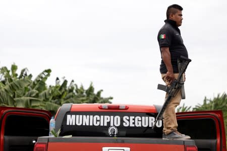 A vigilante stands on the back of a truck while patrolling the municipality of Coahuayana