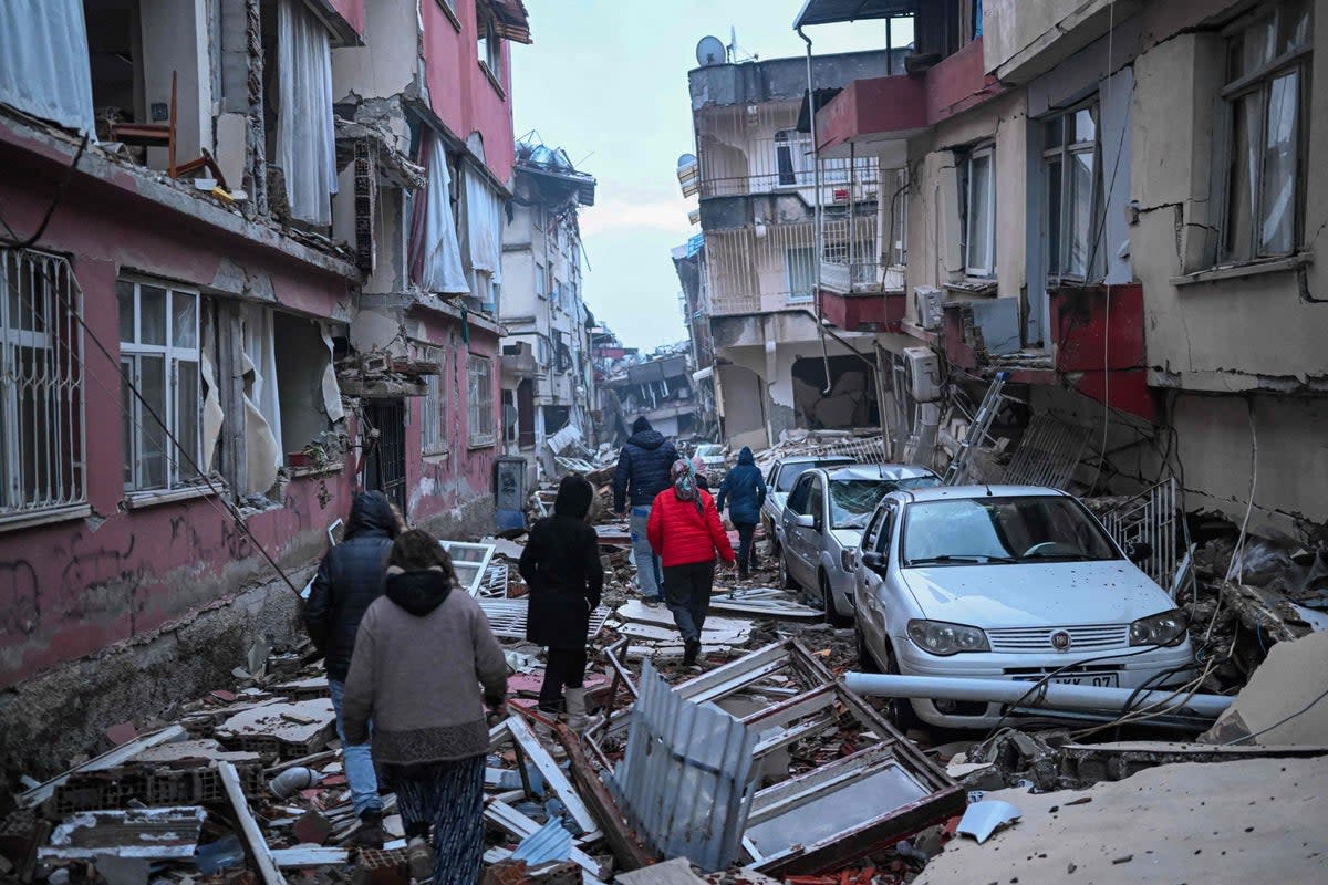 People walk along a street strewn with debris as they look for relatives in Hatay, southeastern Turkey (AFP/Getty)