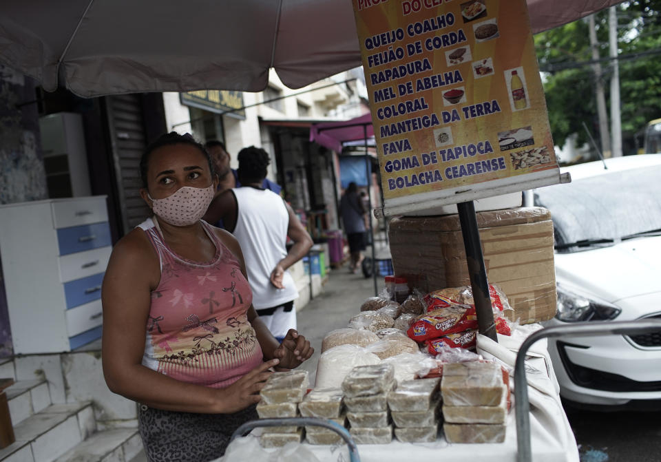 A street vendor wearing a mask amid COVID-19 sells cheese, beans, and sweets in Rio de Janeiro, Brazil, Friday, Oct. 9, 2020. Many people in Brazil are struggling to cope with less pandemic aid from the government and jumping food prices, with millions expected to slip back into poverty. (AP Photo/Silvia Izquierdo)