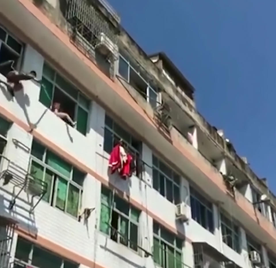A firefighter also tried to push the woman away from the window with a stick (AsiaWire)