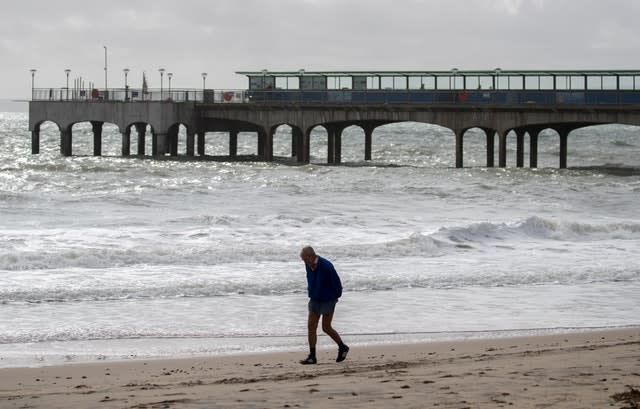 A hardy soul walks along an otherwise deserted Boscombe beach in Dorset