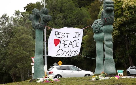 Tributes to Grace Millane are left at the roundabout in Titirangi, at the start of Scenic Drive in Auckland - Credit: Getty