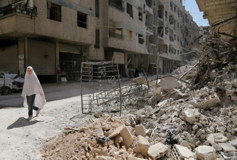 A girl walks past the rubble of a destroyed building in the rebel-held Syrian town of Ayn Tarma, in the Eastern Ghouta region outside the capital Damascus on July 19, 2017