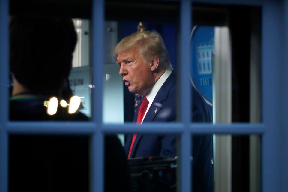 As seen through a window, President Donald Trump speaks about the coronavirus in the James Brady Press Briefing Room of the White House, Tuesday, March 31,