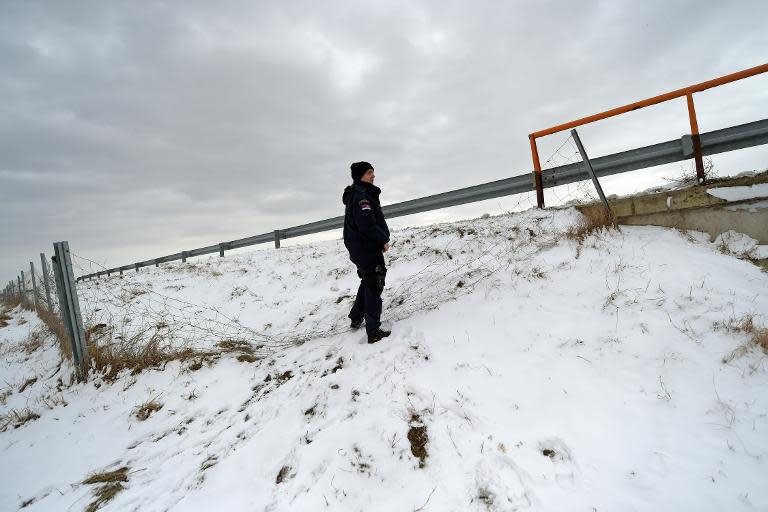 A Serbian border police officer checks a vandalised fence near the Hungarian border in the northern Serbian village of Backi Vinogradi on February 9, 2015