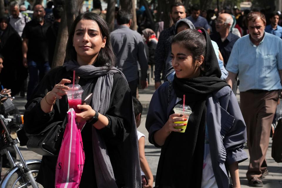 Two women drink a slushy while walking around in the old main bazaar of Tehran, Iran, Saturday, Oct. 1, 2022.