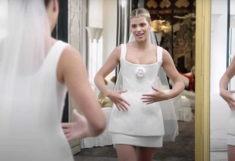 Sofia stands in front of a mirror in her minidress