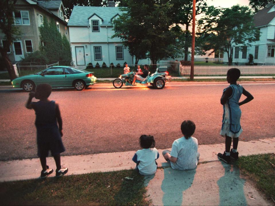 Children sitting on a curb under the glow of a streetlight on a warm summer night in Minneapolis.