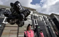 A woman holds balloons at 'Dismaland', a theme park-styled art installation by British artist Banksy, at Weston-Super-Mare in southwest England, Britain, August 20, 2015. REUTERS/Toby Melville