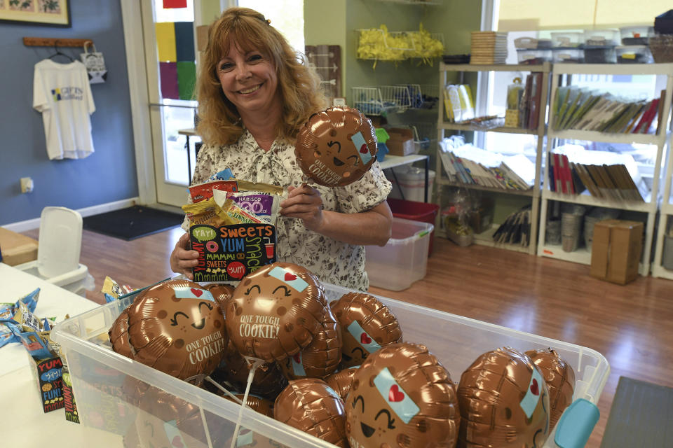 Kim Shanahan, who operates online store Gifts Fulfilled, poses with her "One Tough Cookie" boxes, which the balloons were out of stock for over a year in her shop, Thursday, Sept. 8, 2022, in Berlin, Md. Inflation and rising costs for everything from labor to raw materials have forced many small businesses to raise prices. But customers are feeling the pinch of inflation, too. (AP Photo/Todd Dudek)