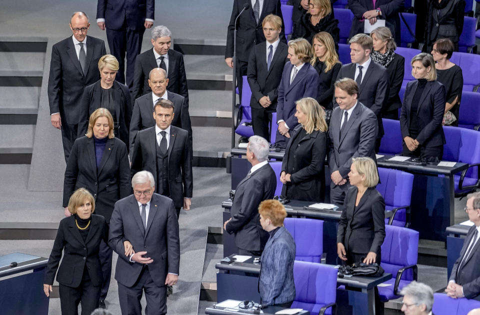 French President Emmanuel Macron, 2nd row right, German President Frank-Walter Steinmeier, first row right, German Chancellor Olaf Scholz, 3rd row right, and Ingeborg Schaeuble, first row left arrive for a state act to commemorate late former German finance minister Wolfgang Schaeuble in the German parliament in Berlin, Germany, Monday, Nov.22, 2024. (AP Photo/Markus Schreiber)