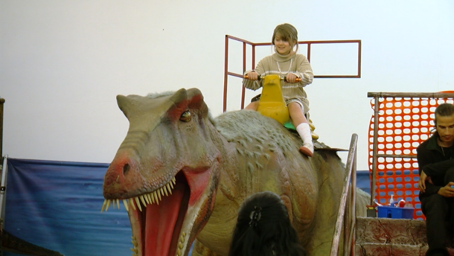 A kid riding a dino at Jurassic Quest