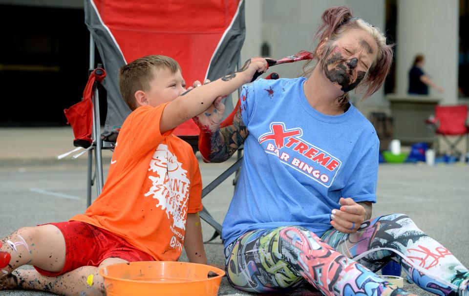 Jasiah Painter, 6, of Springfield gives his aunt, Gina Wehmhoff of Athens, a touch up as they work on their painting on Washington Street between Sixth and Seventh streets during Saturday's "Paint the Street" event in Springfield.