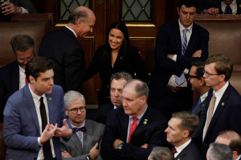 Alexandria Ocasio-Cortez smiles in the background as Republicans argue about electing a new speaker