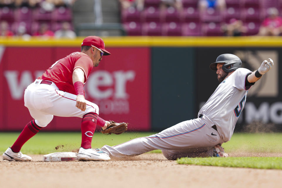 Cincinnati Reds second baseman Matt Reynolds, center left, attempts to tag Miami Marlins' Jacob Stallings as he slides into second base during the seventh inning of a baseball game Thursday, July 28, 2022, in Cincinnati. (AP Photo/Jeff Dean)