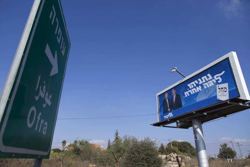 In this Wednesday, Sept. 11, 2019 photo, an election campaign billboard for the Likud party shows Israeli Prime Minister Benjamin Netanyahu and U.S. President Donald Trump, facing a road sign directing traffic to the West Bank Israeli settlement of Ofra, north of Ramallah. The 2.5 million Palestinians living in the West Bank are unable to vote in Israel’s elections next week, which could determine whether it annexes parts of the occupied territory and places their dreams of an independent state even further out of reach. Hebrew reads, "Netanyahu, in another league, the Likud." (AP Photo/Nasser Nasser)