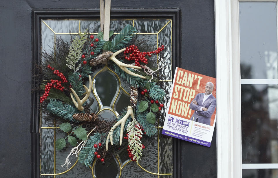 A leaflet from the Working Families Party about the U.S. Senate races is tucked between the door and the frame of a home Wednesday, Dec. 16, 2020, in Lawrenceville, Ga. (AP Photo/Tami Chappell)