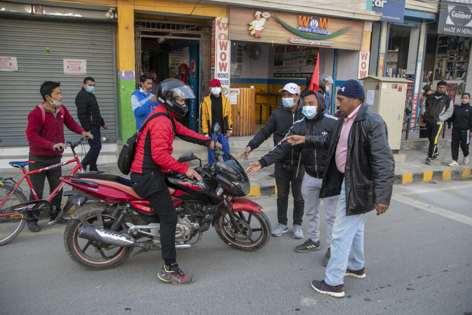 Nepalese demonstrators stop a man riding his bike during a general strike in Kathmandu, Nepal, Thursday, Feb. 4, 2021. A general strike called by a splinter faction of the ruling Communist party paralyzed life in Nepal on Thursday, shutting down schools, transportation and markets. Highways were deserted and shops were closed by the strike protesting Prime Minister Khadga Prasad Oli's decision to dissolve Parliament and call new elections. (AP Photo/Niranjan Shrestha)