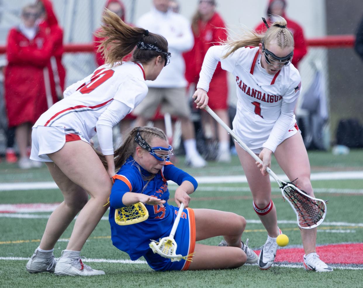 Canandaigua's Hanna Davis, right, wins a draw control while Penn Yan's Taylor Mullins is knocked to the turf by Abigail Cangemi.