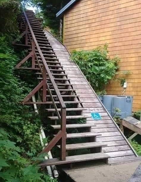 Steep wooden staircase outside with 'good luck' message, appears unsafe