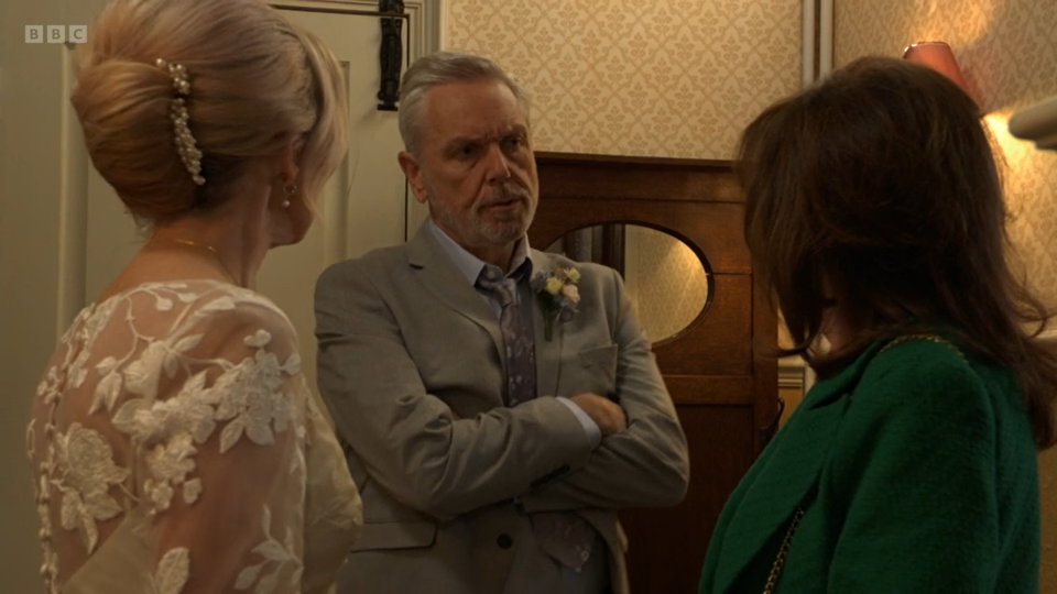 An angry Rocky Cotton with his arms crossed as he and Kathy Beale confront Jo Cotton during their wedding.