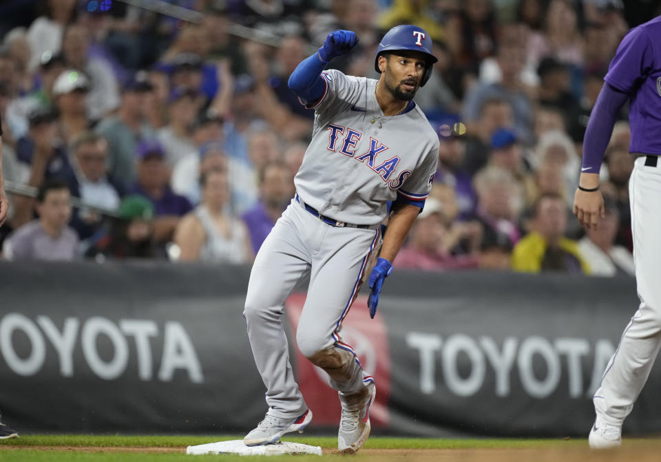 Texas Rangers' Marcus Semien slides safely into third base with an RBI-triple off Colorado Rockies starting pitcher German Marquez in the fifth inning of a baseball game Tuesday, Aug. 23, 2022, in Denver. (AP Photo/David Zalubowski)