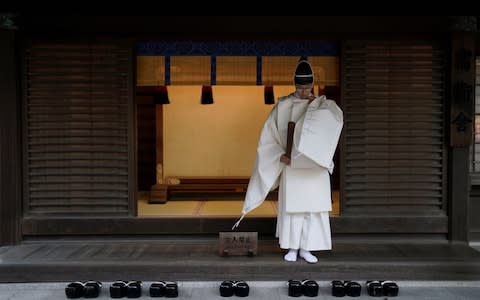 A Shinto priest prepares to attend a ritual to mark the end of the year and prepare for the new one at Meiji Shrine in Tokyo - Credit: Rex