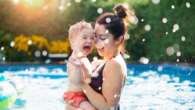 Three years old Little boy with Down syndrome having fun in the swimming pool with his family.