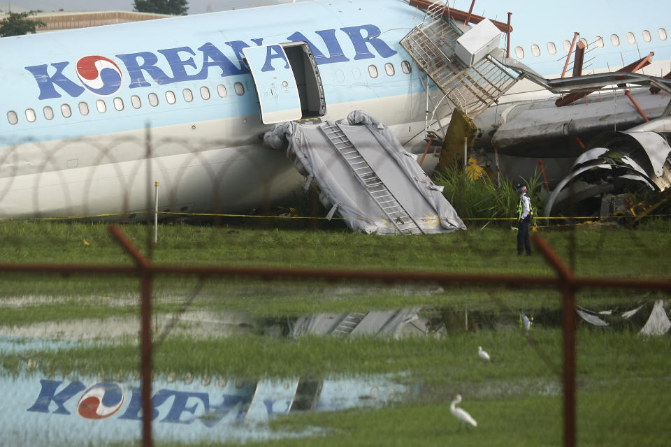 A security guard walks beside a damaged Korean Air plane on Monday Oct. 24, 2022 after it overshot the runway at the Mactan-Cebu International Airport in Cebu, central Philippines. The Korean Air plane overshot the runway while landing in bad weather in the central Philippines late Sunday, but authorities said all 173 people on board were safe. (AP Photo/Juan Carlo De Vela)
