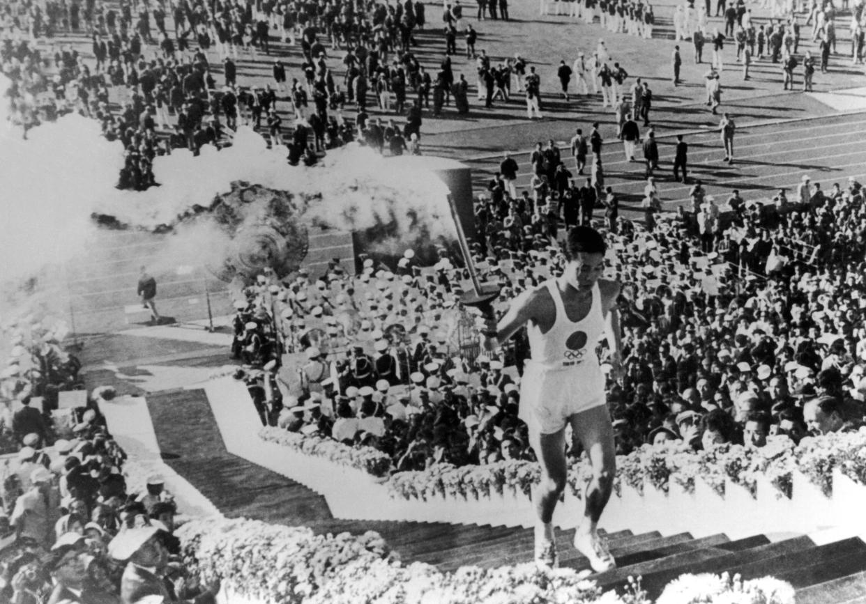 Japan's Yoshinori Sakai, who was born in Hironshima on the day the atomic bomb fell on the city in 1945, climbing up the stairs to light the Olympic cauldron at the 1964 Tokyo Summer Games. 