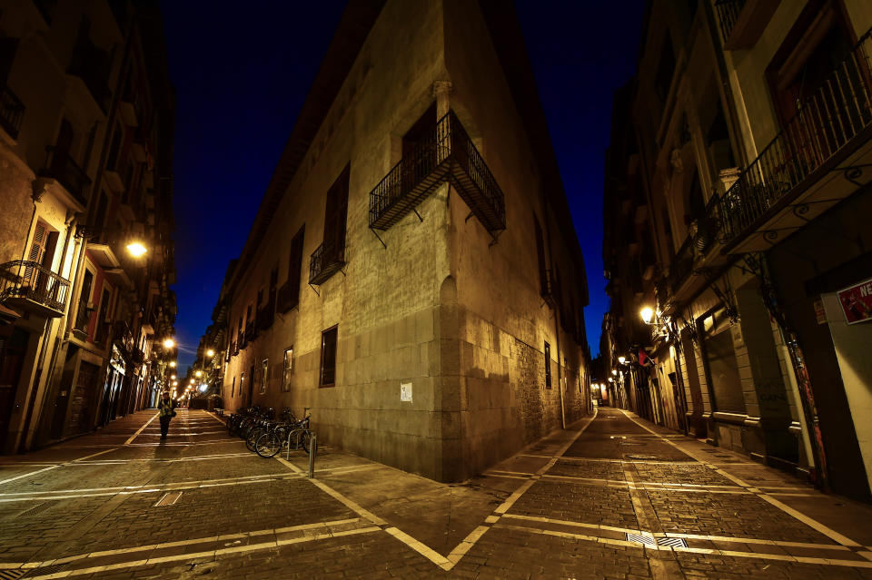 A lone pedestrian walks near to the corner between Major, left, and Jakarta street of the old city, in Pamplona, northern Spain on March 25, 2020. (Alvaro Barrientos/AP)