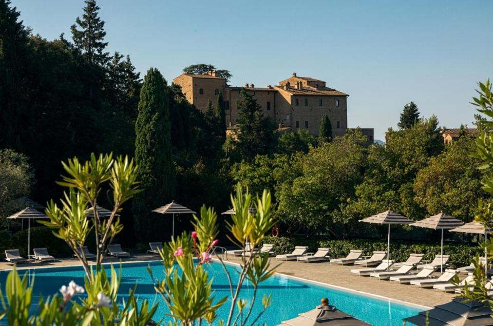 a pool with chairs and umbrellas by a large building