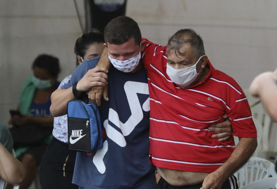 In this April 16, 2020 photo, a patient suspected of suffering from COVID-19 disease. leaves the 28 de Agosto hospital after waiting hours for medical attention in Manaus, Amazonas state, Brazil. The man left with the help of his son, after giving up on waiting for medical attention. (AP Photo/Edmar Barros)