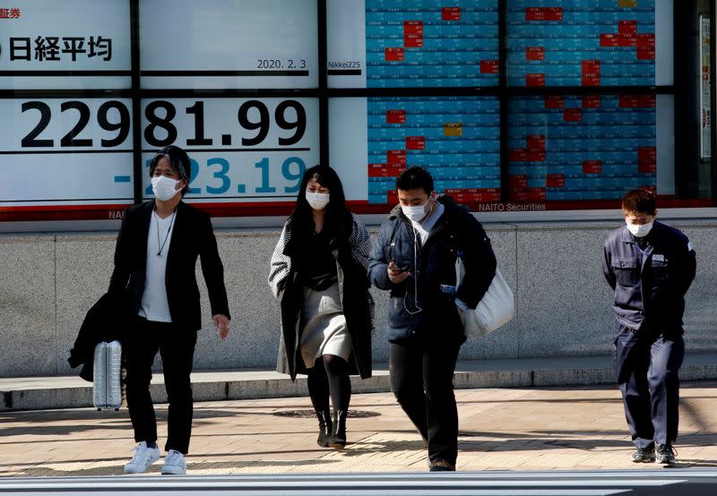 FILE PHOTO: People wearing surgical masks walk past a screen showing Nikkei index outside a brokerage in Tokyo