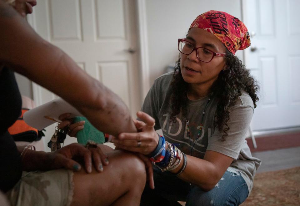 Esther Flores, a nurse who runs the nonprofit 1DivineLine2Health, drop-in safe houses that provide resources for women including victims of human trafficking, domestic violence and those with substance use disorders, examines the infected arm of a visitor to her Hilltop location on July 12, 2021.