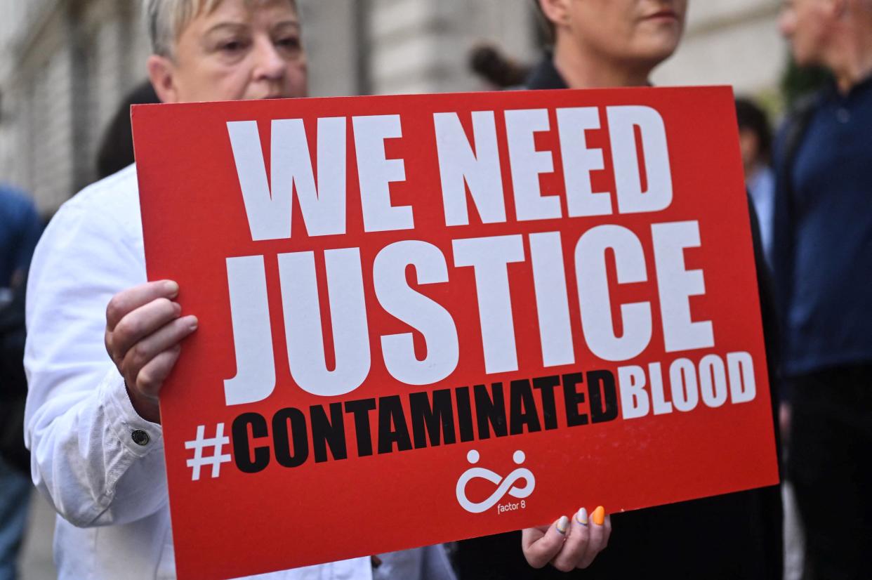 Demonstrators hold placards reading message related to the NHS infected blood scandal as Britain's Prime Minister Rishi Sunak is questioned by Infected Blood Inquiry, in London, on July 26, 2023. About 2,900 people died in the UK after they were given contaminated blood products in the 1970s and 80s. The inquiry is set to examine how thousand of patients in country were infected with HIV and hepatitis C and how authorities and the government, responded to what has been called the worst treatment disaster in the history of the NHS. (Photo by JUSTIN TALLIS / AFP) (Photo by JUSTIN TALLIS/AFP via Getty Images)