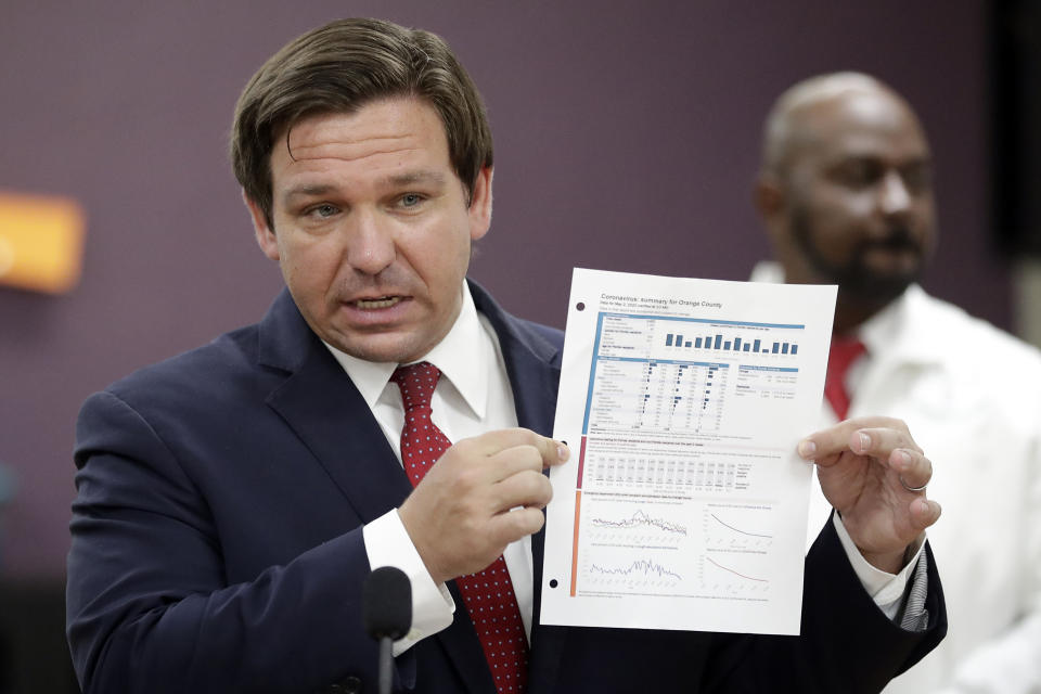 Florida Gov. Ron DeSantis, holds up a graph concerning COVID-19 cases in Florida as he speaks about opening businesses such as barber shops and nail and hair salons during at a news conference Saturday, May 2, 2020, in Orlando, Fla. (John Raoux/AP)