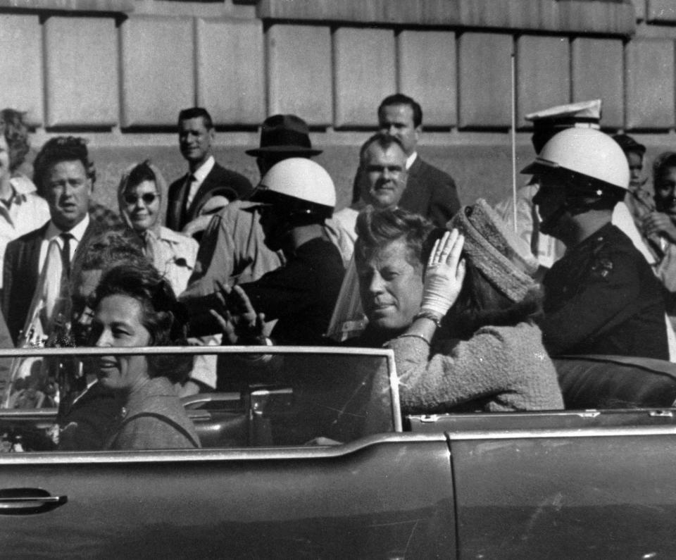 President John F. Kennedy rides in a motorcade with his wife Jacqueline in Dallas, Texas, prior to his assassination