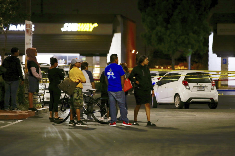 Members of a church group wait behind police lines, fearing they know one person killed by a man stabbing people at a Subway, in Santa Ana, Calif., Wednesday, Aug. 7, 2019. A man killed multiple people and wounded others in a string of robberies and stabbings in California's Orange County before he was arrested, police said Wednesday. (AP Photo/Alex Gallardo)