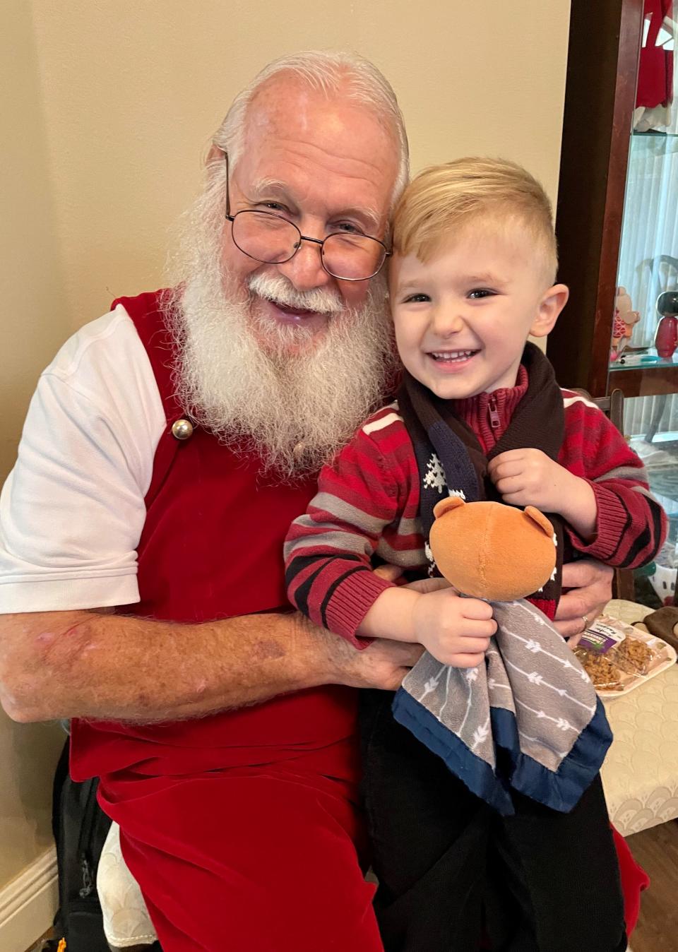 Dressed as Santa Claus, Willard Davis greets 3-year-old Reagan Graybeal at his Suntree home on Christmas Eve.