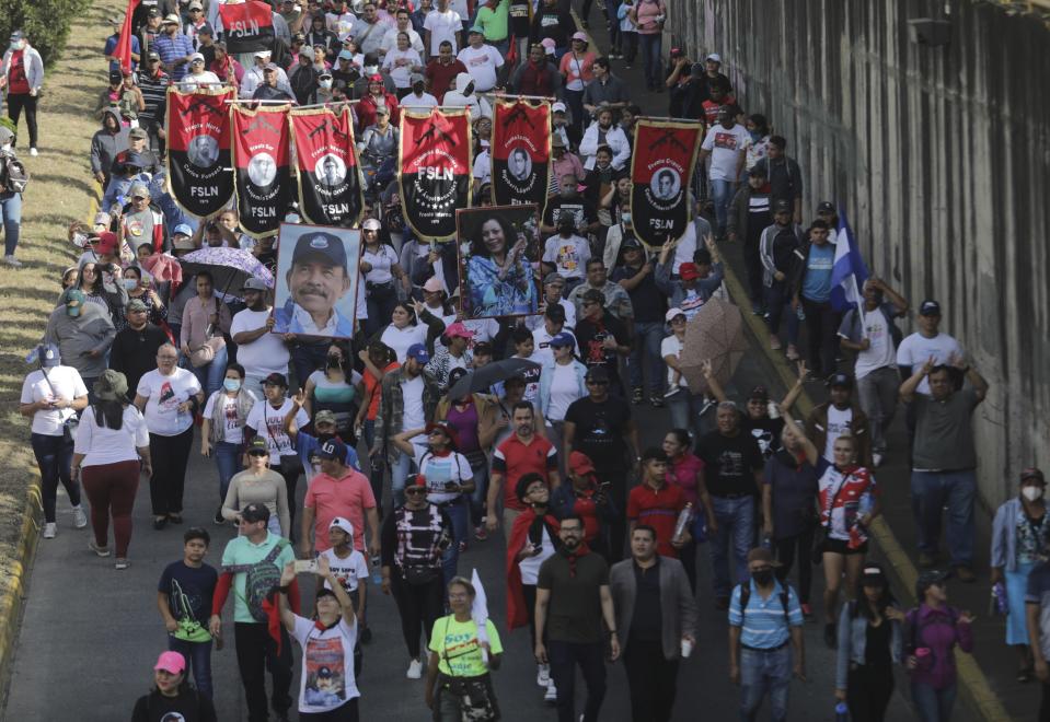 Demonstrators carry Sandinista National Liberation Front banners and a portrait of President Daniel Ortega and Vice President Rosario Murillo, during a pro-government march in Managua, Nicaragua, Saturday, Feb. 11, 2023. (AP Photo)