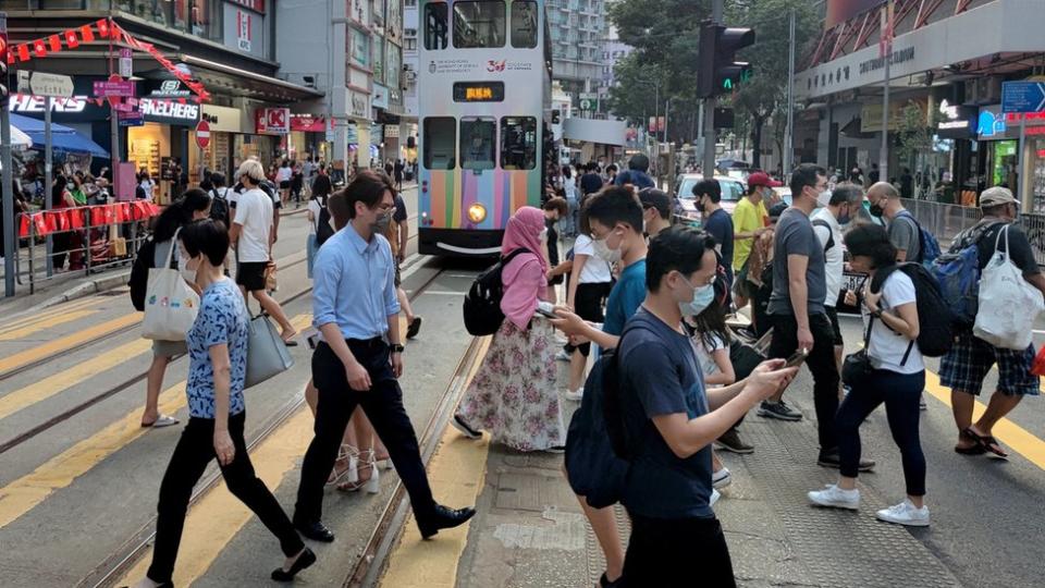 香港灣仔莊士敦道上的過路市民與靠站電車（中新社圖片4/10/2022）