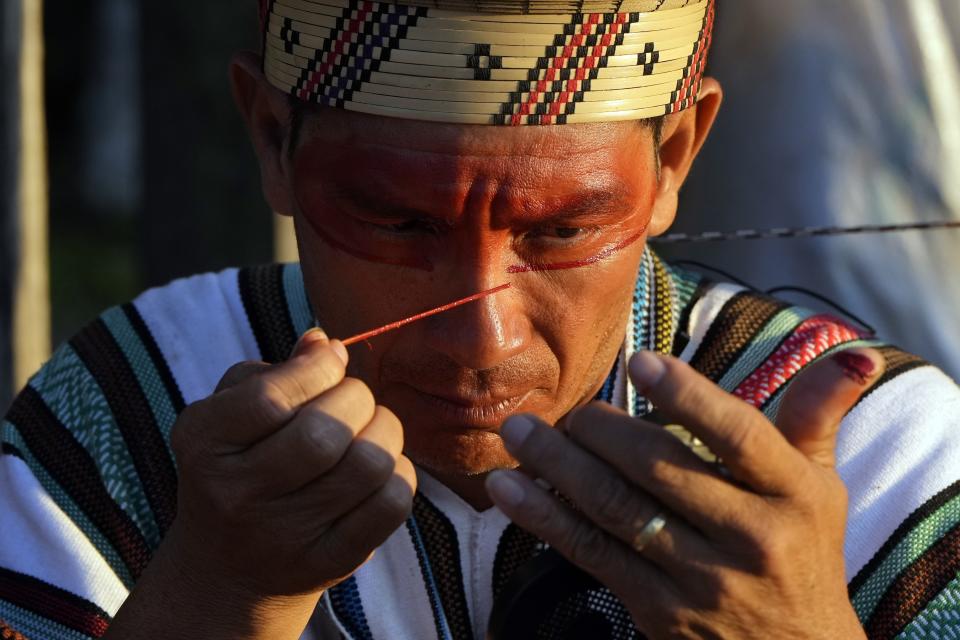 An Ashaninka Indigenous man applies face paint during the annual celebration recognizing the Ashaninka territory in the Apiwtxa village, Acre state, Brazil, Monday, June 24, 2024. (AP Photo/Jorge Saenz)