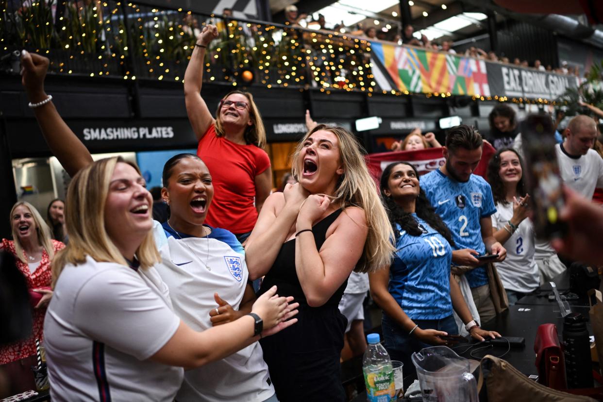 TOPSHOT - England fans celebrate the victory of England as they watch a screen showing the Women's World Cup semi-final football match between Australia and England, at Boxpark Wembley in London on August 16, 2023. England beats Australia 3-1 to reach Women's World Cup final. (Photo by JUSTIN TALLIS / AFP) (Photo by JUSTIN TALLIS/AFP via Getty Images)