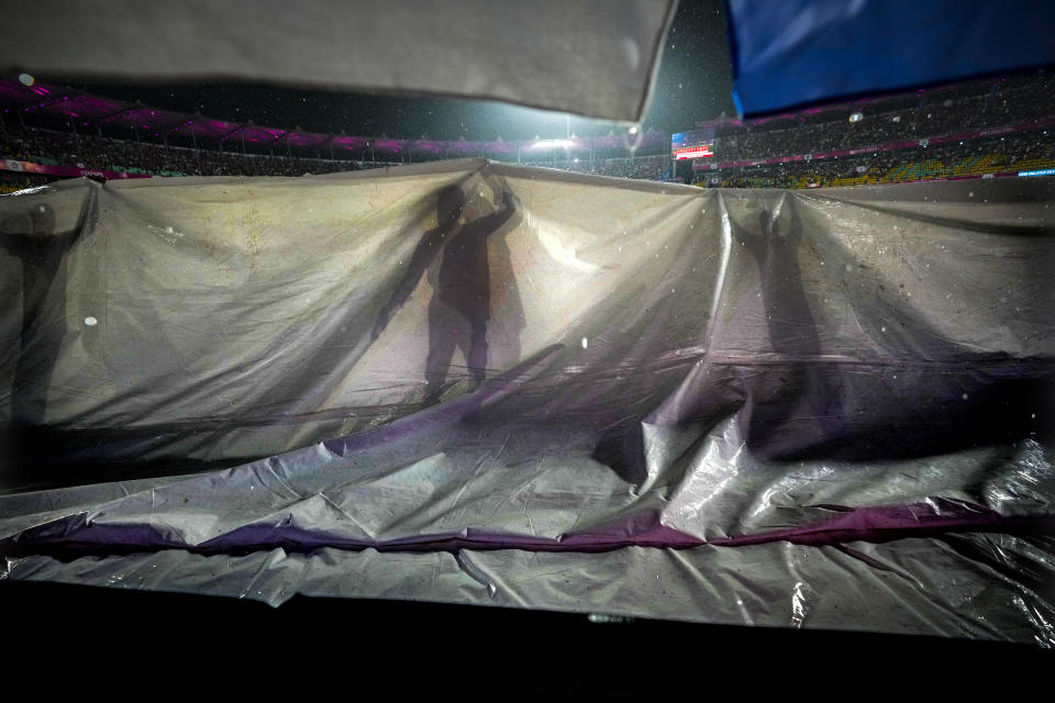 Ground staff pull covers as the rain delayed the start of the Indian Premier League cricket match between Rajasthan Royals and Kolkata Knight Riders in Guwahati, India, Sunday, May. 19, 2023. (AP Photo/Anupam Nath)