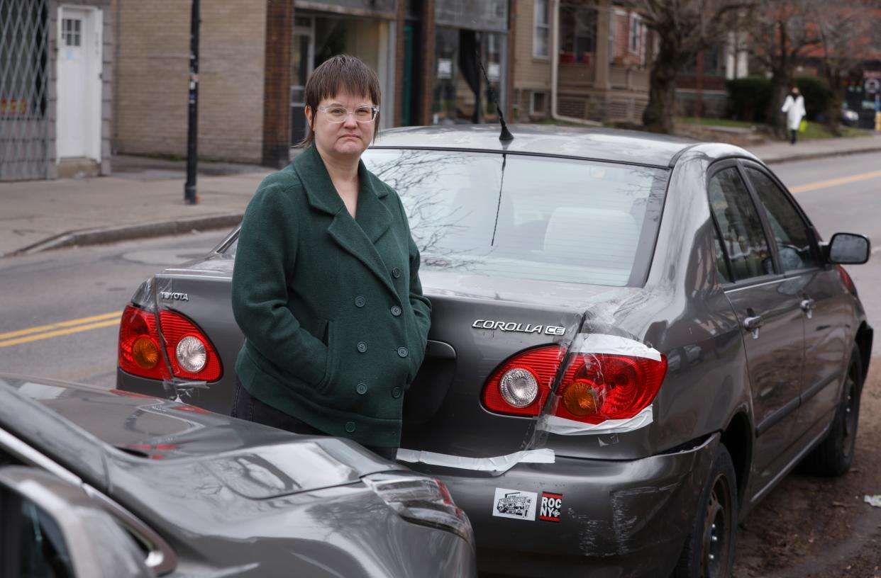 Dina Noto stands alongside her parked Toyota Corolla on Park Avenue, near Rowley Street, in Rochester Monday, March 18, 2024. The car was badly damaged when it got smashed during a police crash. Noto didn't have collision coverage and her claim with the city got denied due in part to the "reckless disregard" standard for emergency responders.
