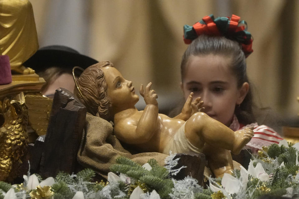 A girl looks at a statue of Baby Jesus as Pope Francis presides over Christmas Eve Mass, at St. Peter's Basilica at the Vatican, Saturday Dec. 24, 2022. (AP Photo/Gregorio Borgia)