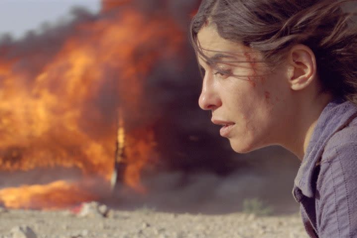Mélissa Désormeaux-Poulin in front of something burning in the background in Incendies (2010).